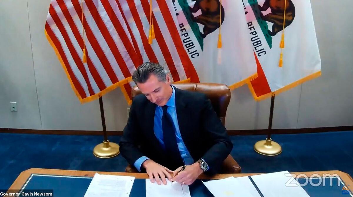 California Gov. Gavin Newsom signs into law a bill that establishes a task force to come up with recommendations on how to give reparations to Black Americans in Sacramento, Calif., on Sept. 30, 2020. (Office of the Governor via AP)