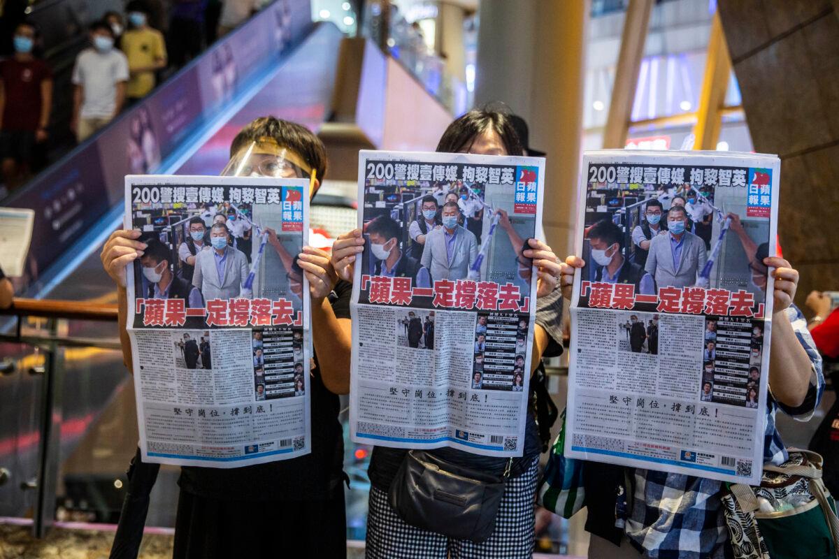People hold up copies of the Apple Daily as they protest for press freedom inside a mall in Hong Kong on Aug. 11, 2020. (Isaac Lawrence/AFP via Getty Images)
