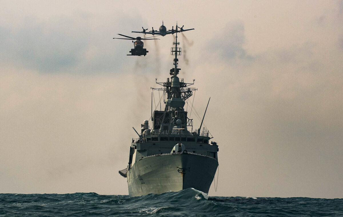 A CH-148 Cyclone helicopter and a CP-140 Aurora maritime patrol aircraft fly over HMCS WINNIPEG as part of a photo exercise in the Asia-Pacific Region during Operation NEON on Nov. 15, 2020. (Sailor 1st Class Valerie LeClair, MARPAC Imaging Services/CAF Combat Camera via Flickr)