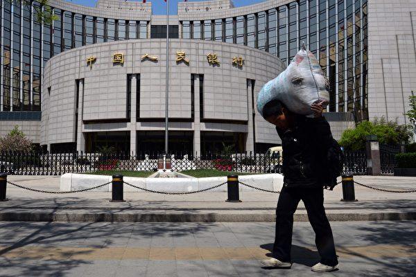 A Chinese migrant worker walks by the People's Bank of China (PBOC) in Beijing on May 1, 2013. The PBOC released the "Financial Stability Law (Draft for Comments)" on April 6, 2022, saying that resolving financial risks is a "constant theme." (Mark Ralston/AFP/Getty Images)