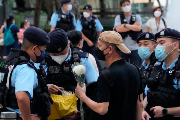 Police officers stop and search a man holding a flower at Hong Kong's Victoria Park on June 4, 2022. (Kin Cheung/AP Photo)