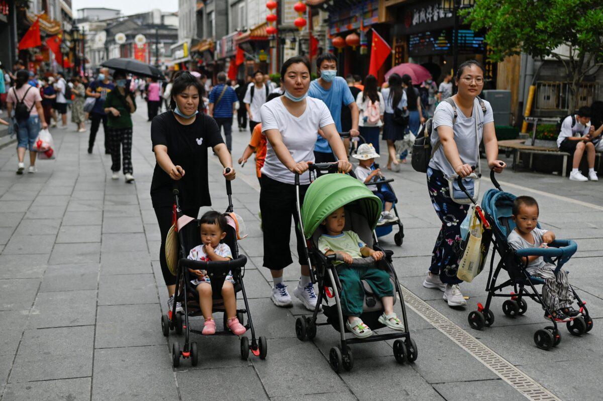 People push baby strollers along a business street in Beijing on July 13, 2021. (Wang Zhao/AFP via Getty Images)