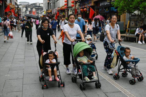 Women push baby strollers along a business street in Beijing on July 13, 2021. (Wang Zhao/AFP via Getty Images)