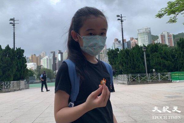 Rourou, a 10 year-old girl, showed a candle-shaped plastic block in her hand to the reporter. She came to Causeway Bay today with her family, passing by the outside of Victoria Park. (Tang Jianfeng/The Epoch Times)