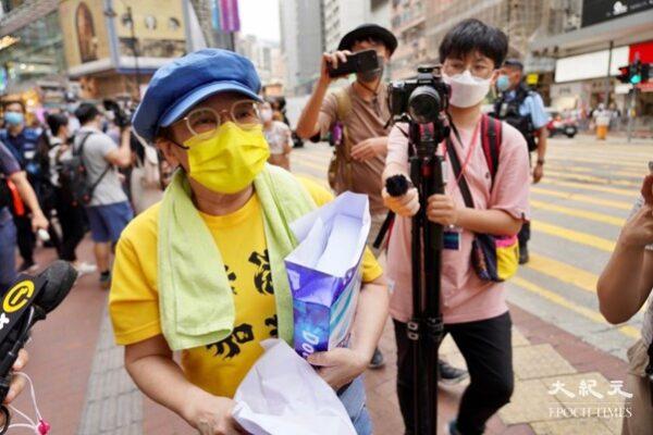 Lady wearing a yellow top with the words “Go Hong Kong” was handing out blank A4 sheets. The police tried to stop her. (Yu Gang/The Epoch Times)