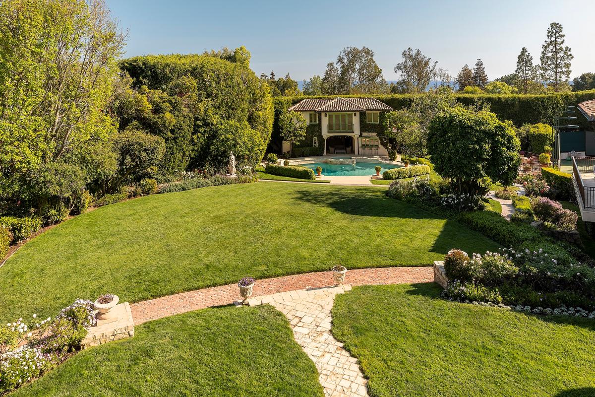 An inviting guest house is located beyond the pool, with expansive lawns and stone and brick walkways snaking through the property. (Jim Bartsch/Jade Mills)