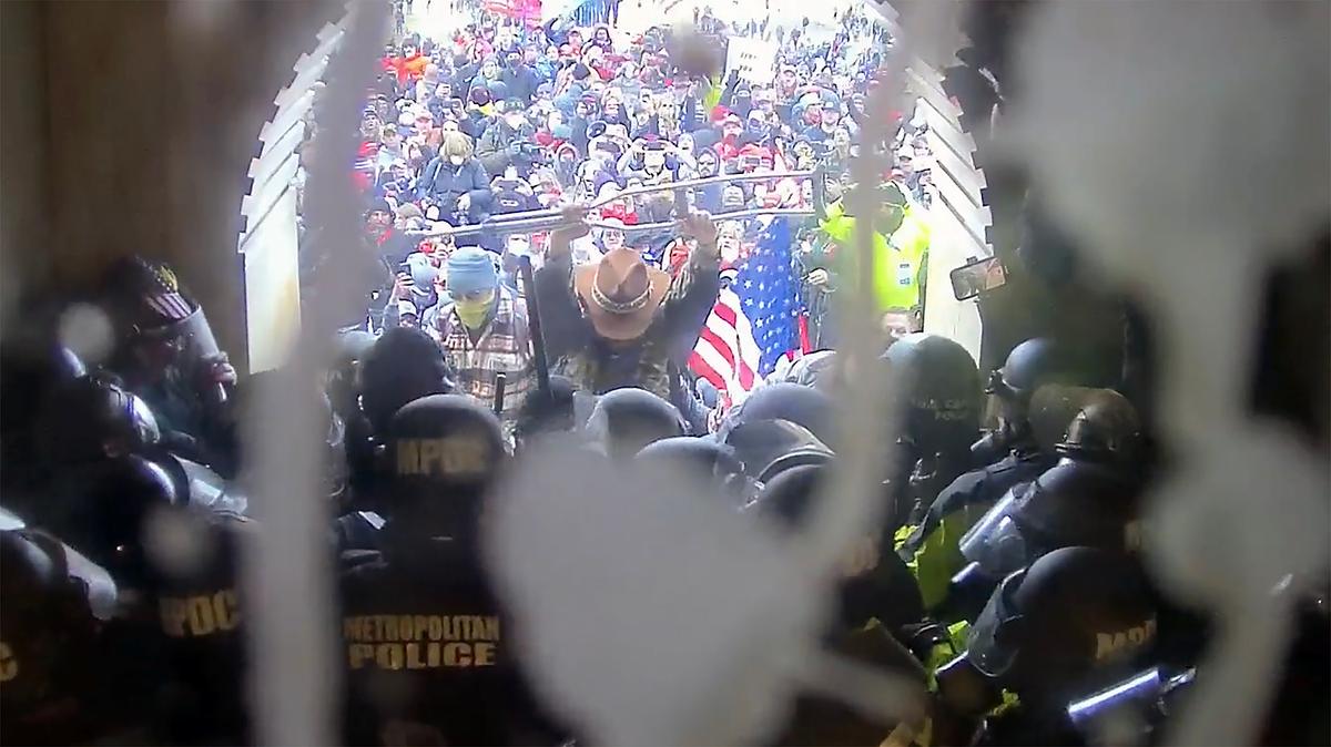 Luke Coffee holds up a crutch as he stands in the breach between police and the crowd at the Lower West Terrace tunnel. "In the name of Jesus, please stop!" he said. (U.S. Capitol Police/Screenshot via The Epoch Times)