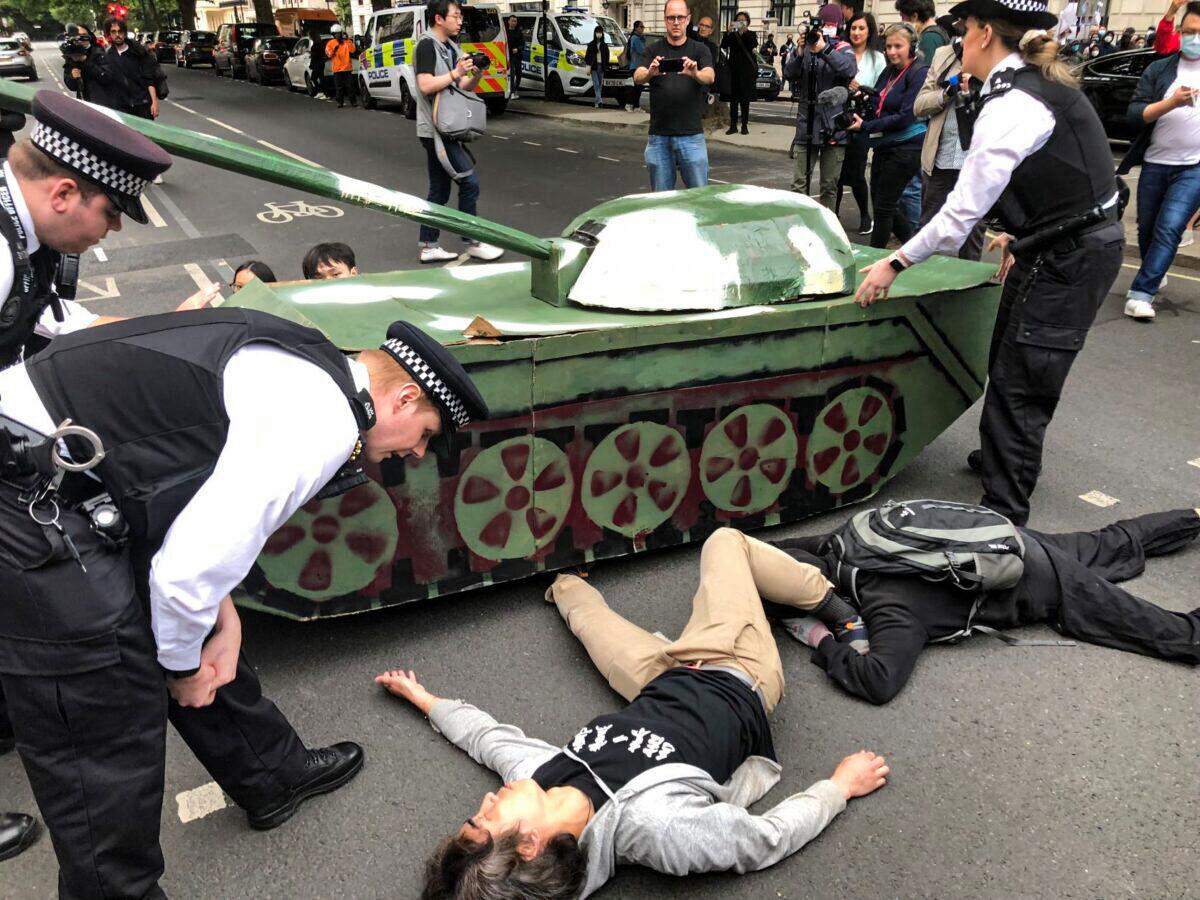 Police seek to remove protesters lying under a model tank outside the Chinese Embassy during the 33rd Tiananmen Square massacre remembrance event in London on June 4, 2022. (Peter Simpson/The Epoch Times)