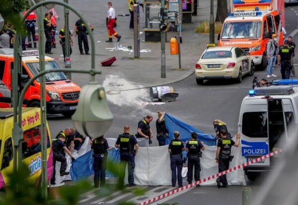 Police officers cover a dead body after a car crashed into a crowd of people in central Berlin, Germany, on June 8, 2022. (Michael Sohn/AP Photo)