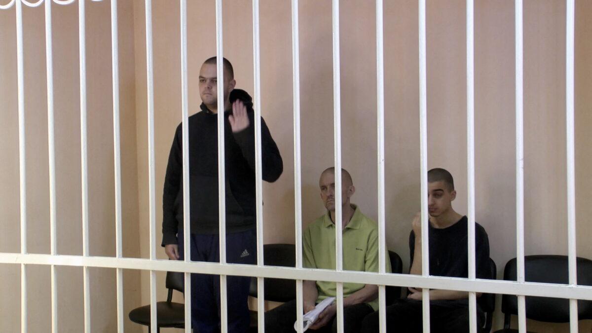 Britons Aiden Aslin, Shaun Pinner and Moroccan Brahim Saadoun captured by Russian forces during a military conflict in Ukraine, in a courtroom cage at a location given as Donetsk, Ukraine, on June 7, 2022, in a still from video. (Supreme Court of Donetsk People's Republic/Handout via Reuters)