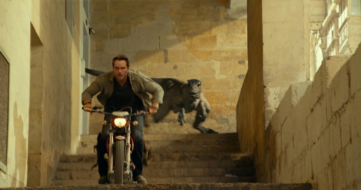 Chris Pratt as Owen Grady flees an angry velociraptor in "Jurassic World: Dominion." (Amblin Entertainment/Universal Pictures)
