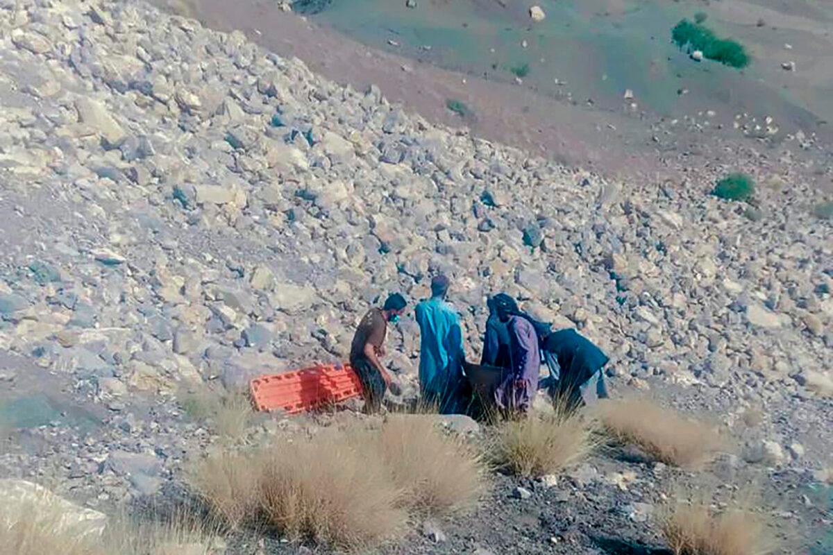 A rescue worker and volunteers remove a body from the site of a bus crash, in Qilla Saifullah, a district in Pakistan's southwest Baluchistan province, on June 8, 2022. (Qadir Baluch/AP Photo)