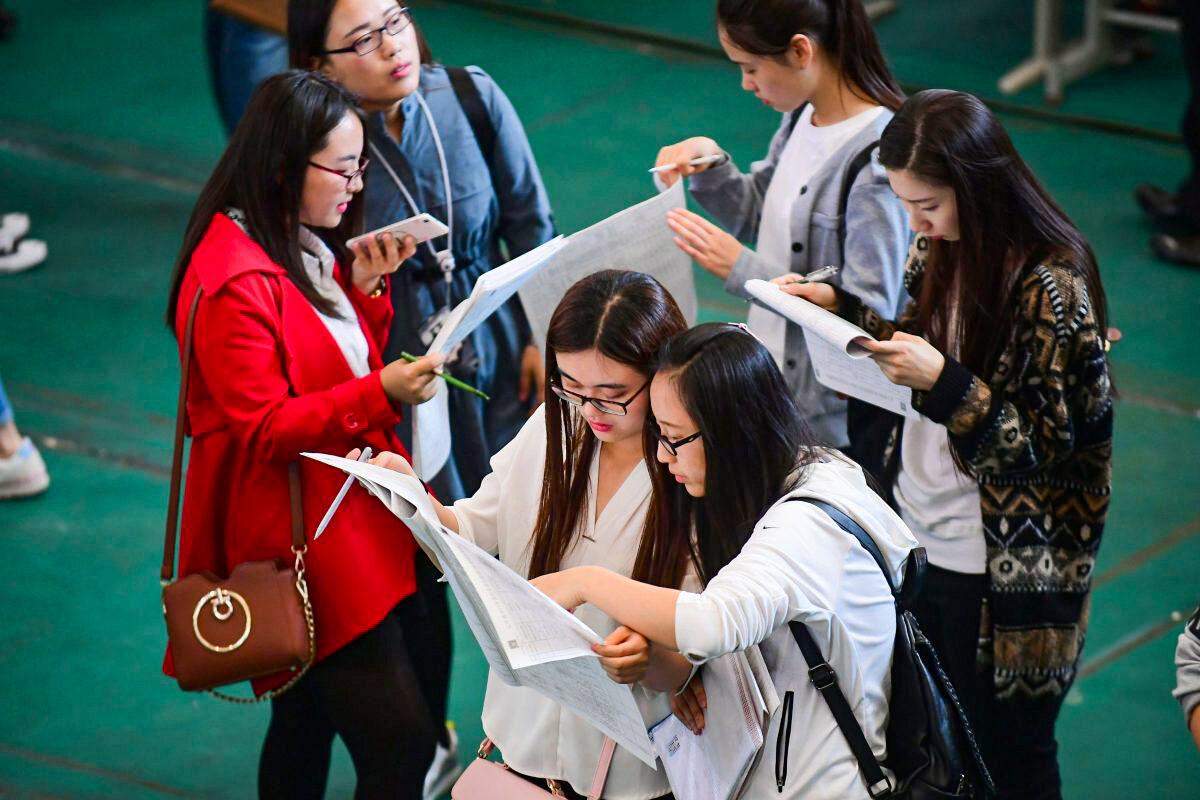 Young adults look at postings at a job fair at Shenyang Aerospace University in Shenyang, China's northeast Liaoning Province, on May 13, 2017. (STR/AFP/Getty Images)