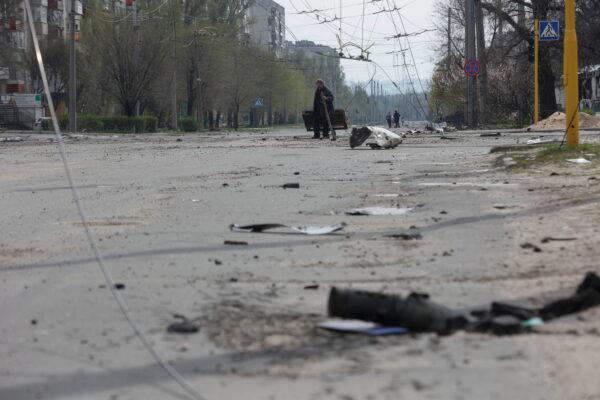 A local resident walks along an empty street with residential buildings damaged by a military strike, in Sievierodonetsk, Luhansk, Ukraine, on April 16, 2022. (Serhii Nuzhnenko/Reuters)