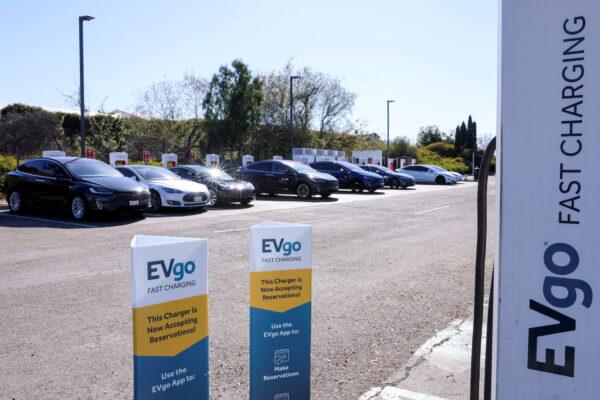 People charge their electric cars at a Tesla station next to an EVgo electric charging location in Carlsbad, Calif., on March 7, 2022. (Mike Blake/Reuters)