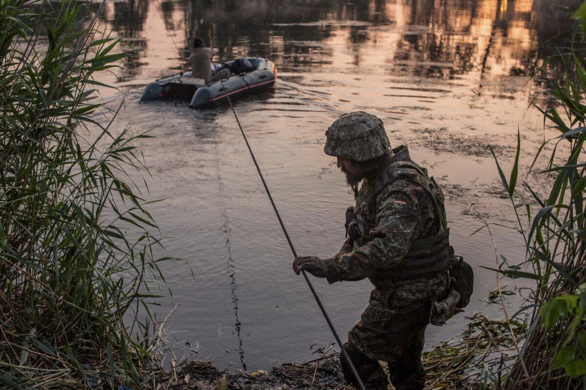 Ukrainian service members cross a river outside the city of Sievierodonetsk, Ukraine, on June 19, 2022. (Oleksandr Ratushniak/Reuters)