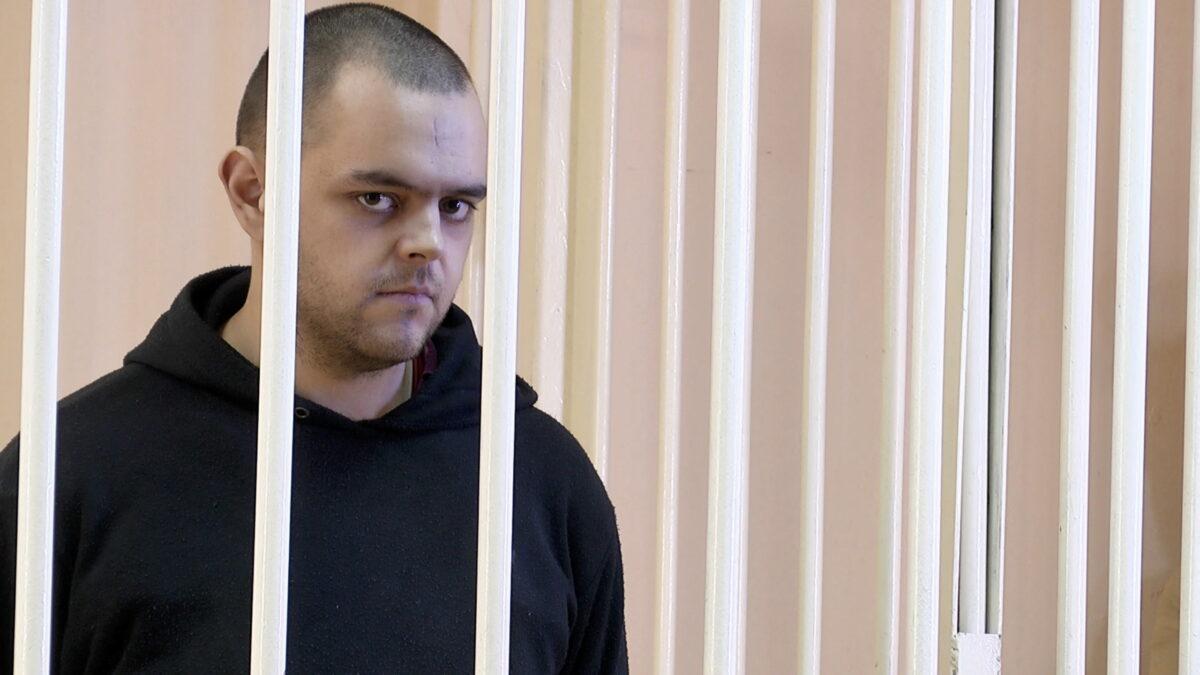 British citizen Aiden Aslin in a courtroom cage at a location given as Donetsk, Ukraine, in a still image from a video released on June 8, 2022. (Supreme Court of Donetsk People's Republic/Handout via Reuters TV)