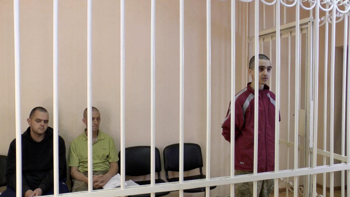 Britons Aiden Aslin and Shaun Pinner and Moroccan Brahim Saadoun captured by Russian forces during a military conflict in Ukraine, in a courtroom cage in Donetsk on June 8, 2022. (Supreme Court of Donetsk People's Republic/Handout via Reuters TV)