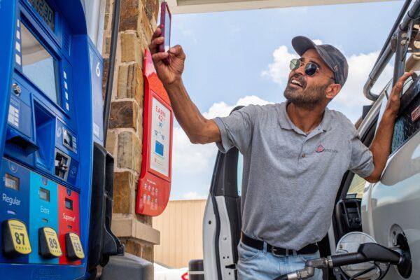 Guy Benhamou sends a picture of gas prices to friends while pumping gas at an Exxon Mobil gas station in Houston, Texas, on June 9, 2022. (Brandon Bell/Getty Images)