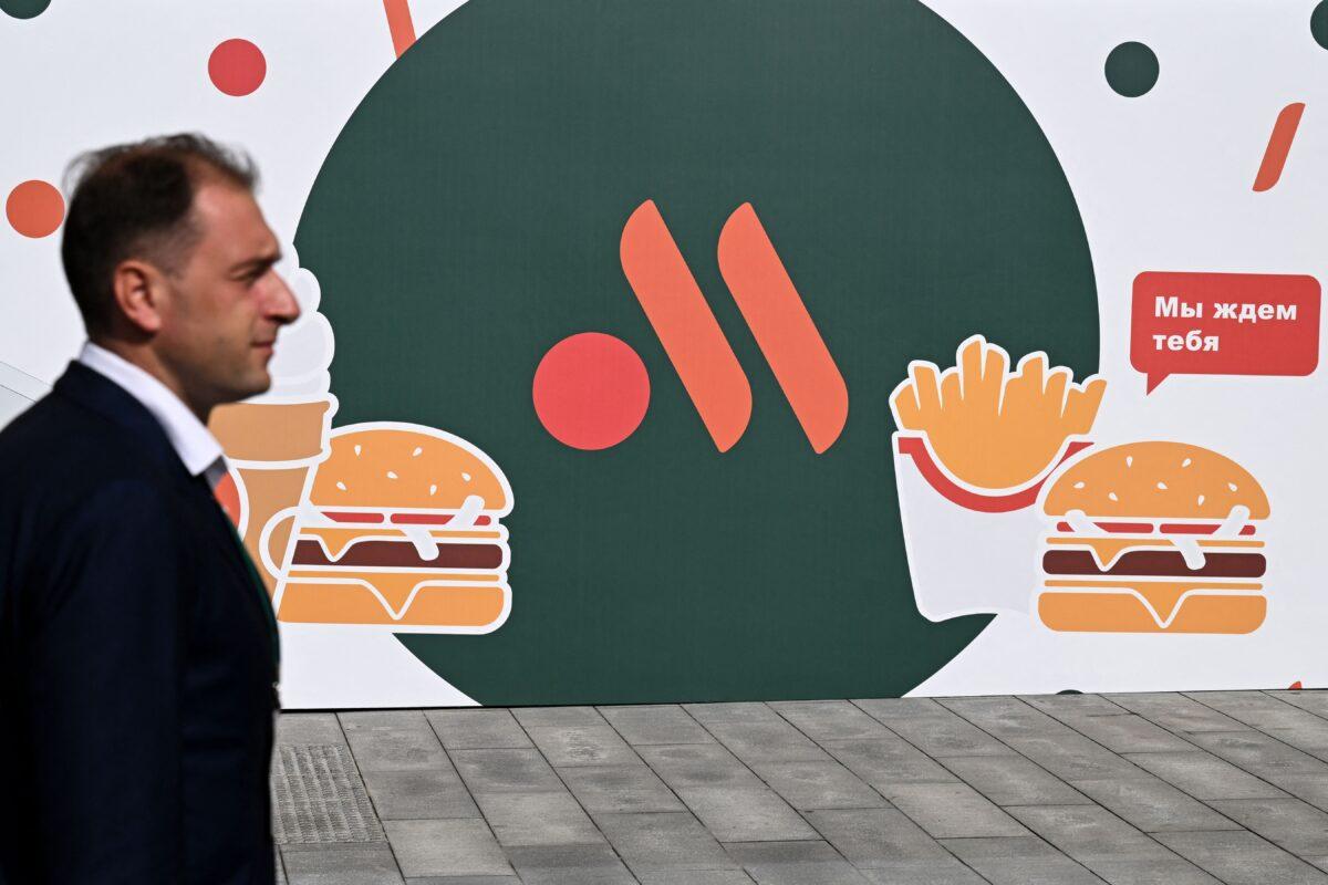 An employee stands in front of the new logo of the Russian version of a former McDonald's restaurant before the opening ceremony, in Moscow on June 12, 2022. (Kirill Kudryavtsev/AFP via Getty Images)