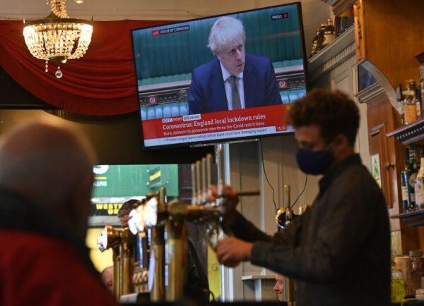 A television shows Britain's Prime Minister Boris Johnson speaking in London as customers sit at the bar inside the Richmond Pub in Liverpool, England, on Oct. 12, 2020. (Paul Ellis/AFP via Getty Images)