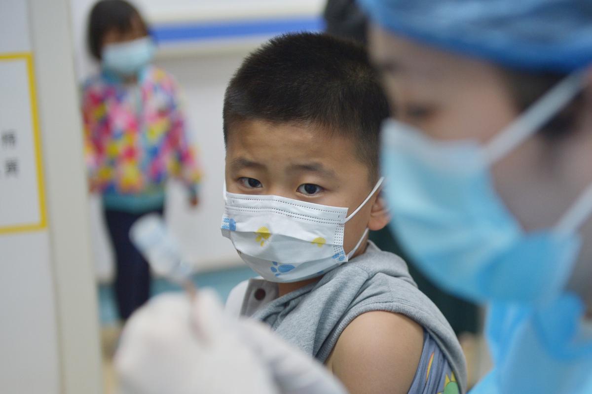 A boy looks at a nurse preparing a jab at a health center in Qingdao in east China's Shandong province on Nov. 04, 2021. (Feature China/Future Publishing via Getty Images)