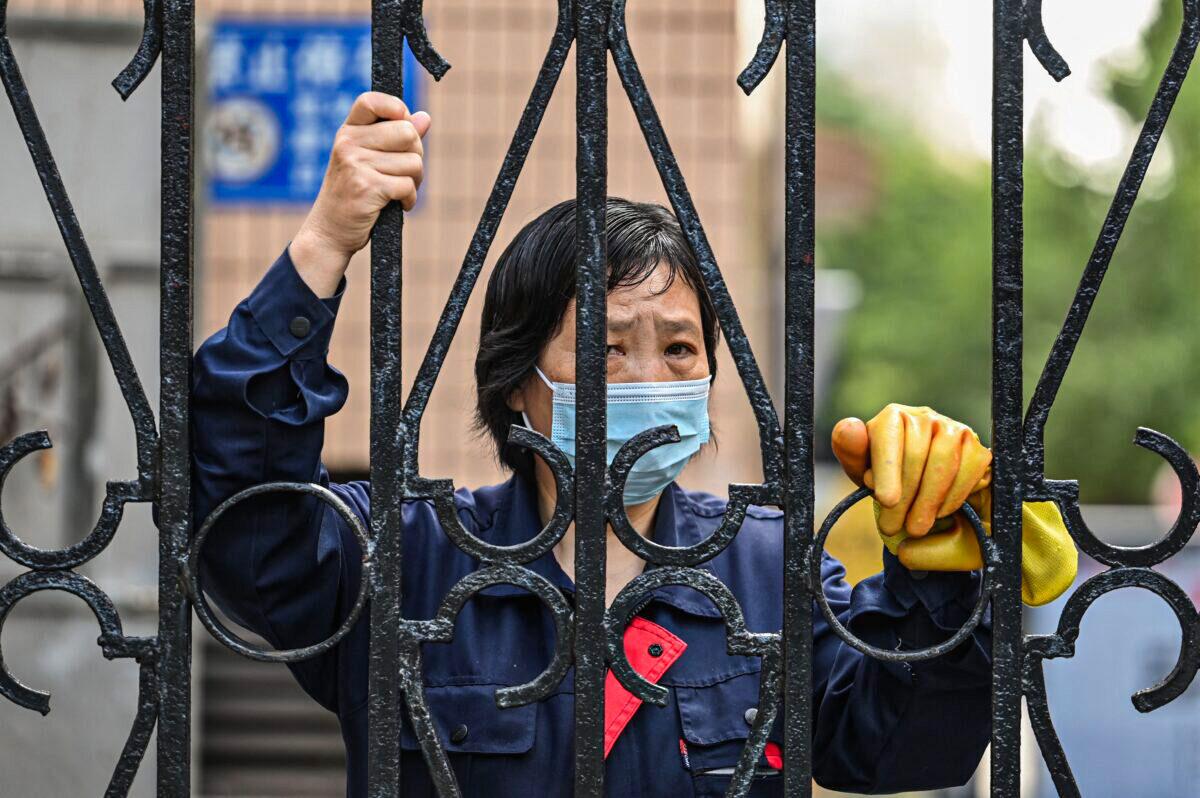 A worker looks past a fence in a compound during a COVID-19 lockdown in the Jing'an district of Shanghai on May 25, 2022. (Hector Retamal/AFP via Getty Images)