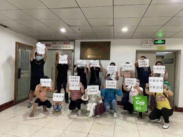 Customers of the four banks in Henan Province hold papers that say “Return our deposits Henan” in Zhengzhou city, Henan Province. (Provided to The Epoch Times)