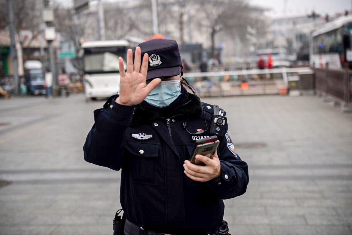 A police officer gestures to a journalist not to photograph in Beijing, China, on March 5, 2021. (Nicolas Asfouri/AFP via Getty Images)