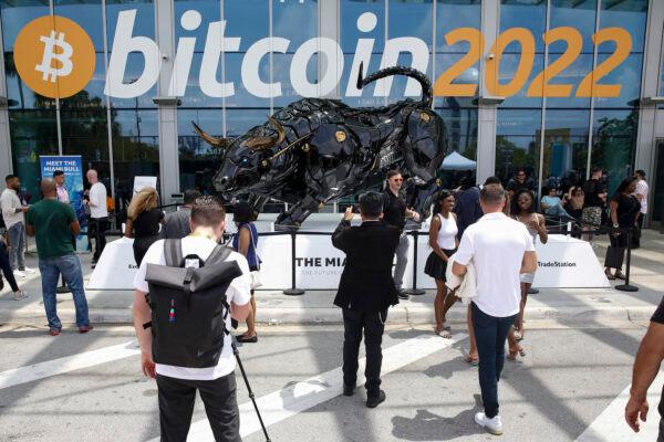 Attendees pose for photos in front of The Miami Bull during the Bitcoin 2022 Conference at Miami Beach Convention Center on April 7, 2022. (Marco Bello/Getty Images)