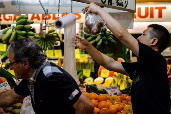 Shoppers are seen using a single-use plastic bag at a fruit and vegetable store inside the Central Market in Adelaide, Australia, on Nov. 1, 2019. (AAP Image/Morgan Sette)