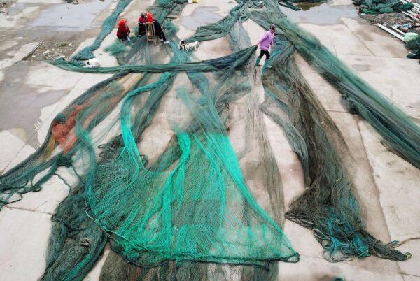 Chinese fisherfolk clear up their fishing nets at a port in Lianyungang in China's eastern Jiangsu Province on April 24, 2019. (STR/AFP via Getty Images)
