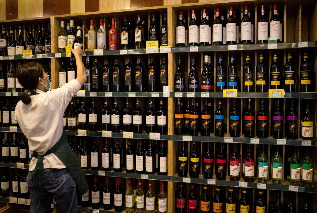 An employee works as Australian-made wine (on display shelves on R) are seen for sale at a store in Beijing on Aug. 18, 2020. China on Aug. 18 ramped up tensions with Australia after it launched a probe into wine imports from the country, the latest salvo in an increasingly bitter row between the trade partners. (Noel Celis/AFP via Getty Images)