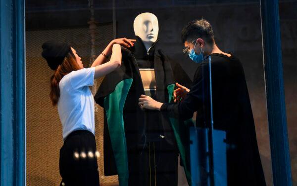 Employees dress a mannequin by a window as retail shops prepare to open in Melbourne, Australia, on Oct. 27, 2020. (William West/AFP via Getty Images)
