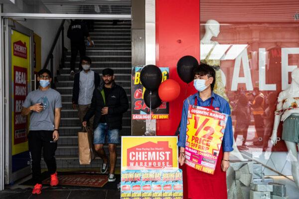 A Chemist Warehouse employee holds a sale signage in Melbourne, Australia, on Dec. 26, 2021. (Diego Fedele/Getty Images)