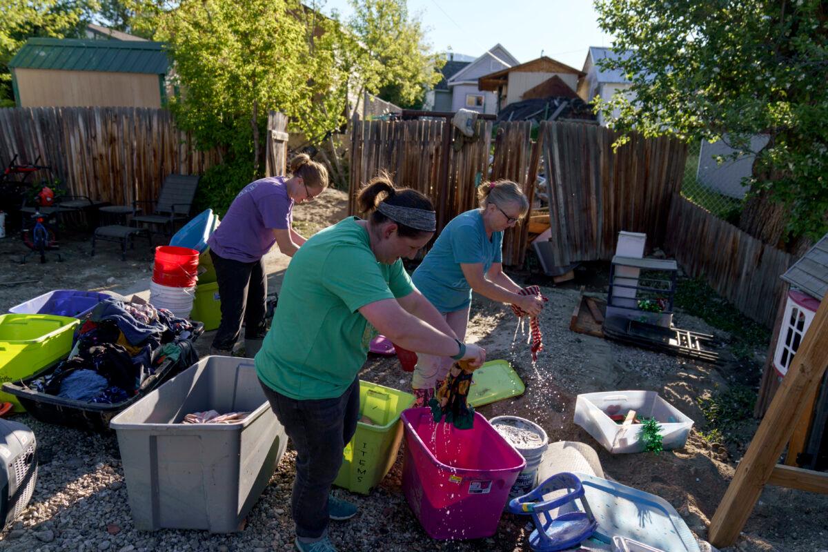 Kirstyn Brown, (L), cleans out damaged clothing from her flooded home with the help of her mother, Cheryl Pruitt, (R), and her sister-in-law, Randi Pruitt, in Red Lodge, Mont., on June 15, 2022. (David Goldman/AP Photo)