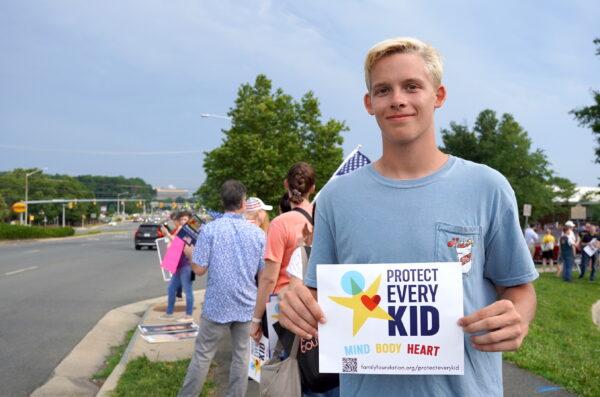  Lars Griffin, a college student who graduated from a Fairfax County high school last year, protests the new “malicious misgendering” policy in the student handbook outside of the school board meeting by Gallows Road outside of the Luther Jackson Middle School in Falls Church, Va., on June 16, 2022. (Terri Wu/The Epoch Times)