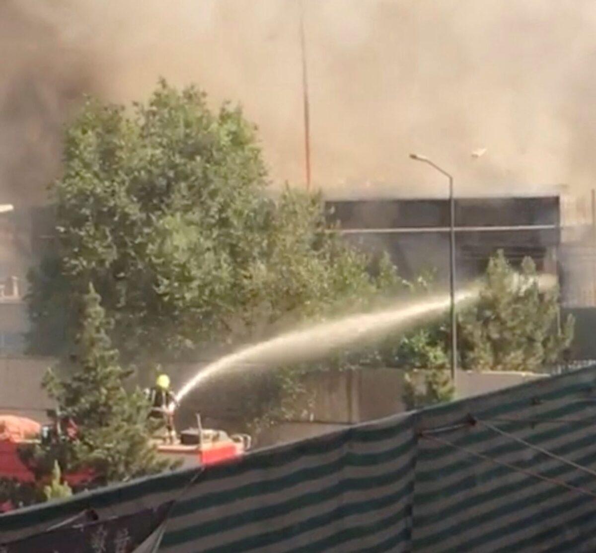 Firefighters try to hose down a fire at a building near a Sikh temple following a blast in a car loaded with explosives in Kabul, Afghanistan, on June 18, 2022, in this still from video. (Social media video via Reuters)