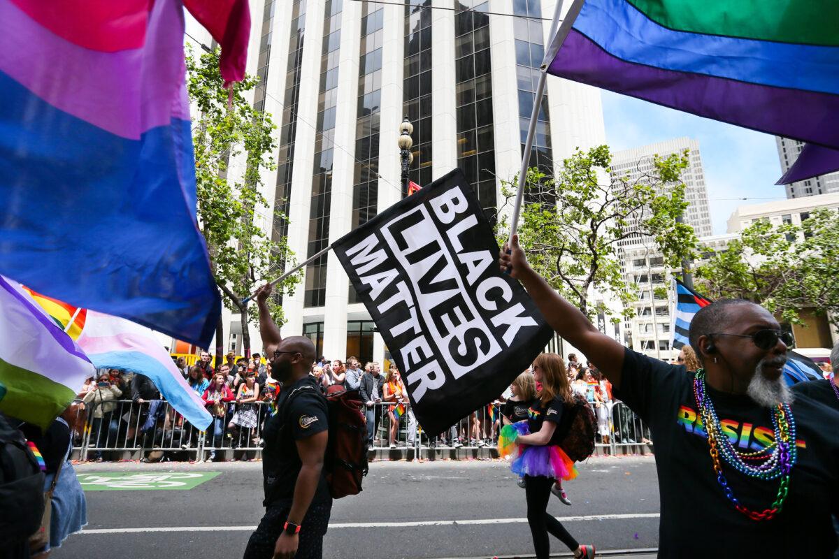 Men wave rainbow and Black Lives Matter flags while marching in the Pride Parade in San Francisco in June 2017. (Elijah Nouvelage/Getty Images)