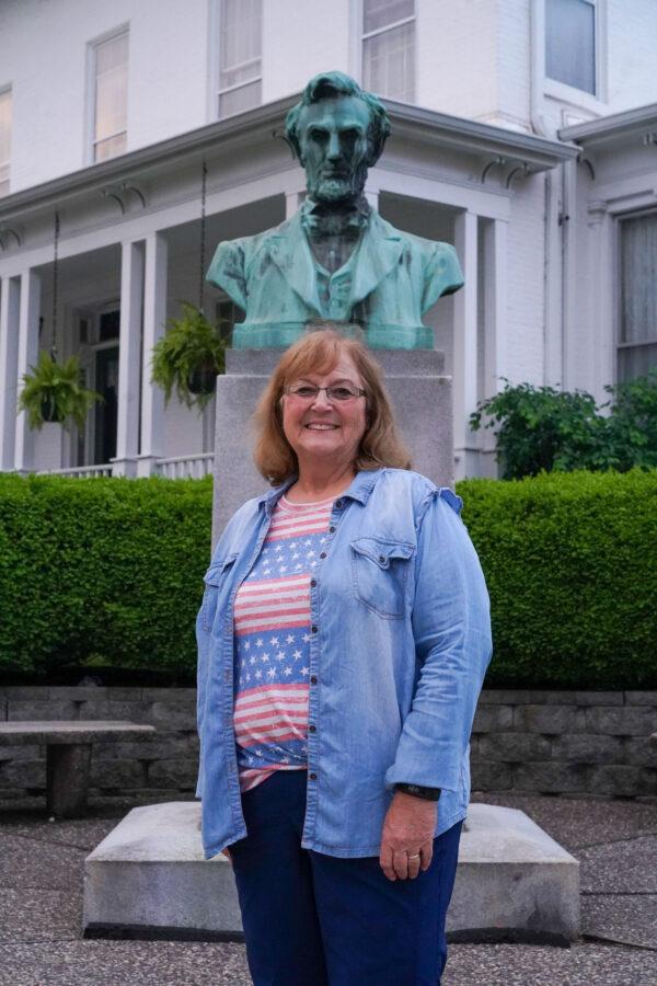 Jan Weber stands in front of a Lincoln Statue in downtown Genesco, Ill., on June 6, 2022. Her farm lies just seven miles north of Genesco. (Cara Ding/The Epoch Times)