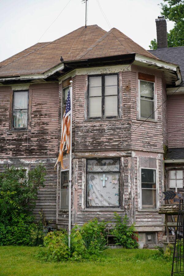 A torn American flag hung on a pole in front of a rundown house in Galesburg, Ill., on June 7, 2022. (Cara Ding/The Epoch Times)