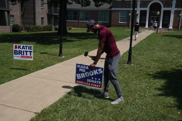 A supporter of Rep. Mo Brooks (R-Ala.) hammers a campaign sign into the ground outside a polling place at Huntingdon College in Montgomery, Ala., on June 21, 2022. (Jackson Elliott/The Epoch Times)