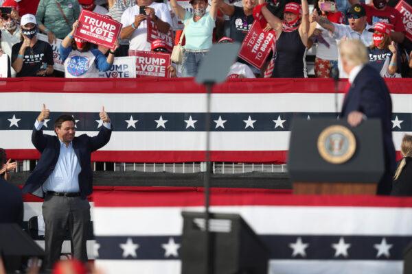 Florida Gov. Ron DeSantis gives two thumbs up toward then-U.S. President Donald Trump after he asked him how it was going in the state as he speaks during his campaign event at The Villages Polo Club in The Villages, Florida on Oct. 23, 2020. (Joe Raedle/Getty Images)