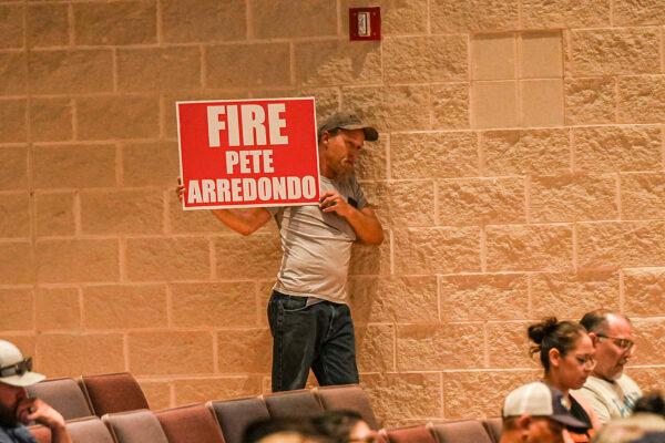A man holds a "Fire Pete Arredondo" sign at the Uvalde Consolidated Independent School District meeting in Uvalde, Texas, on June 20, 2022. (Charlotte Cuthbertson/The Epoch Times)