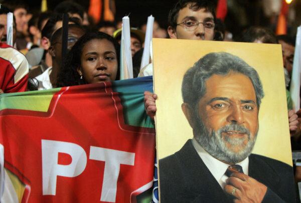 Supporters of the Brazilian President Luiz Inacio Lula da Silva hold a Workers' Party flag and a painting of Lula da Silva during a rally on Sept. 1 2006, in Juiz de Fora, Brazil. (Antonio Scorza/AFP via Getty Images)