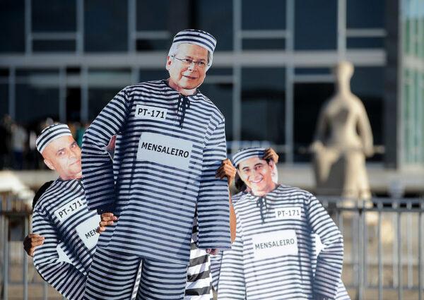 Demonstrators hold images of Brazilian politicians Jose Dirceu (C) and Joao Paulo Cunha (R) and publicist Marcos Valerio, some of the defendants in the trial known as "mensalao," with prison clothes, in front of the Supreme Court headquarters in Brasilia, Brazil, on Aug. 3, 2012. (Pedro Ladeira/AFP/GettyImages)