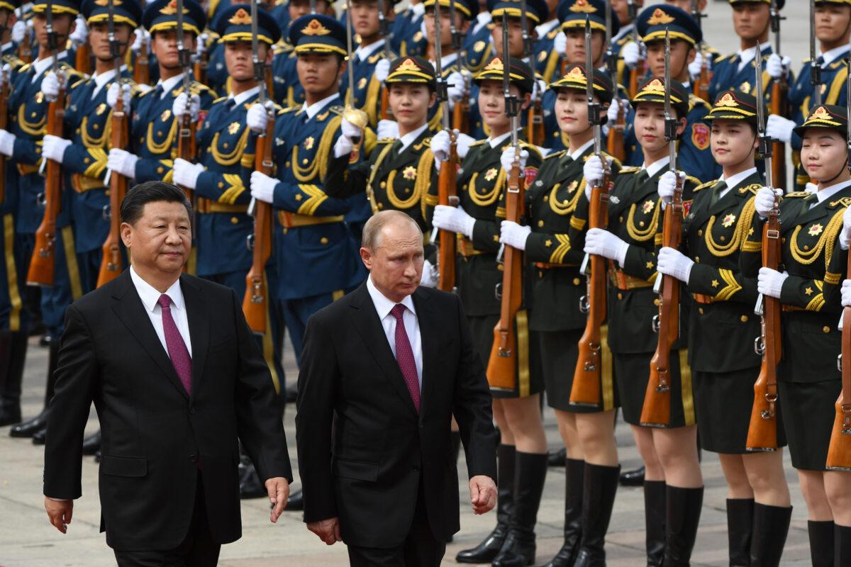 Russia's President Vladimir Putin (C) reviews a military honour guard with Chinese President Xi Jinping (L) during a welcoming ceremony outside the Great Hall of the People in Beijing on June 8, 2018. (Greg Baker/POOL/AFP via Getty Images)