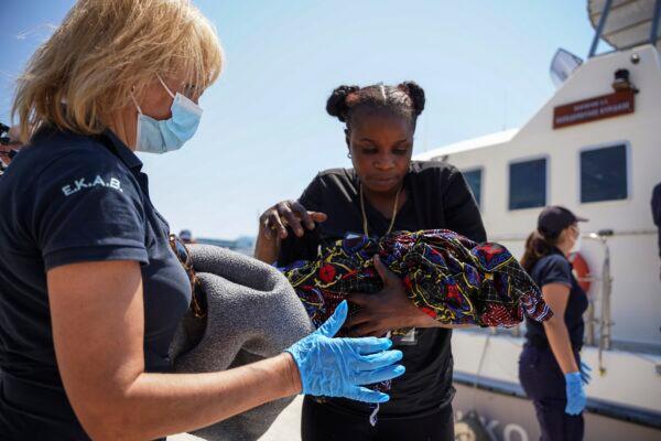 A migrant woman carries a newborn boy at Mytilene port, on the northeastern Aegean Sea island of Lesbos, Greece, on June 22, 2022. (Panagiotis Balaskas/AP Photo)