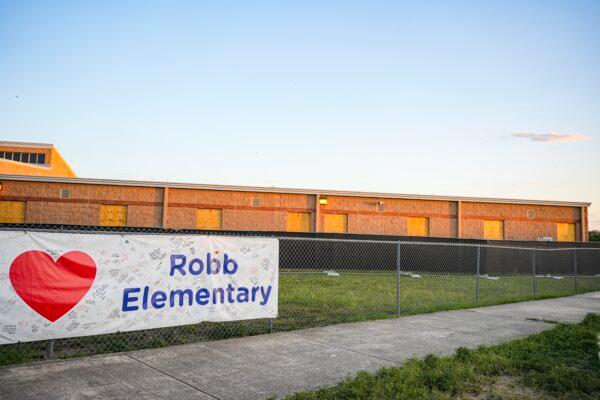 A banner hangs on a fence outside Robb Elementary School, the site of a mass shooting on May 24 in Uvalde, Texas, on June 21, 2022. (Charlotte Cuthbertson/The Epoch Times)