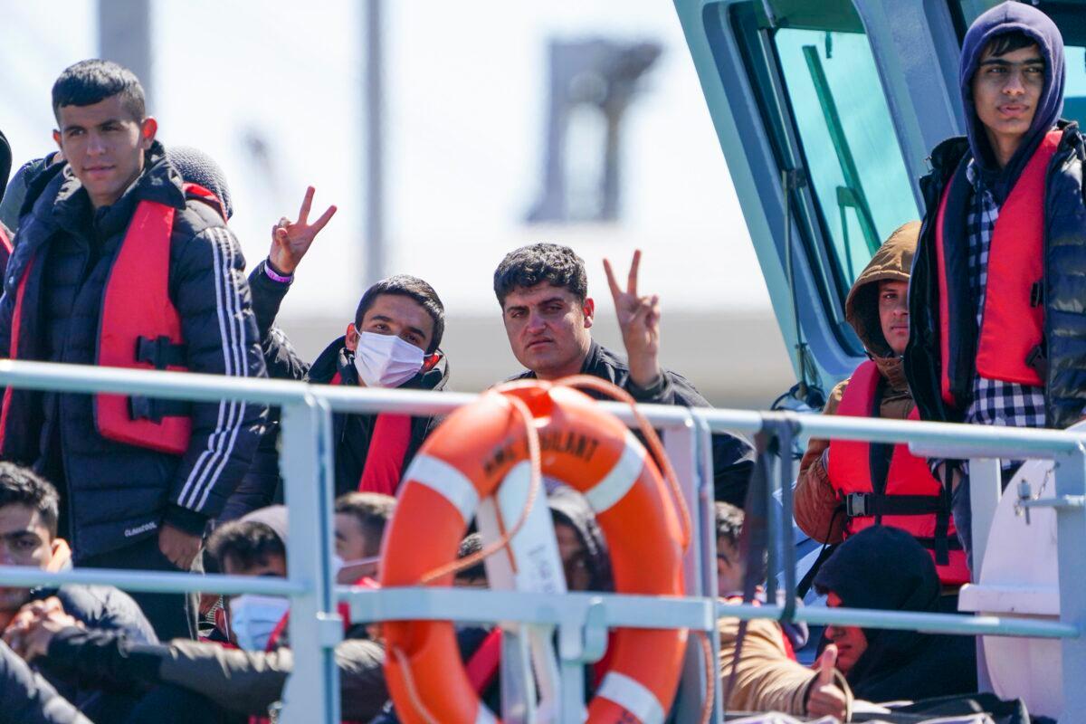 Illegal immigrants who crossed the English Channel from France give V signs on UK Border Force boat Valiant as they arrive in the port of Dover, England, on June 14, 2022. (Chris Eades /Getty Images)